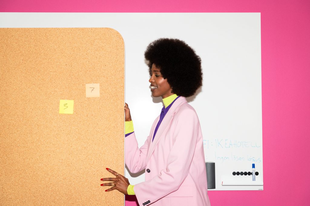 Woman pushing a mobile whiteboard with pinned notes on it