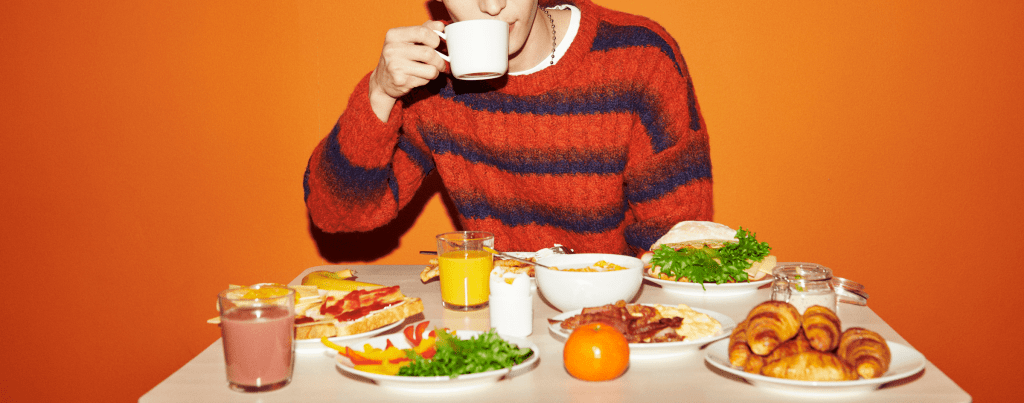 En person som sitter vid ett bord fyllt med mat från IKEA Hotells frukostbuffé.