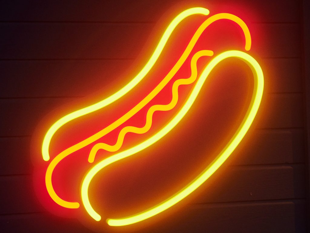 Neon sign of a hotdog in a bun.