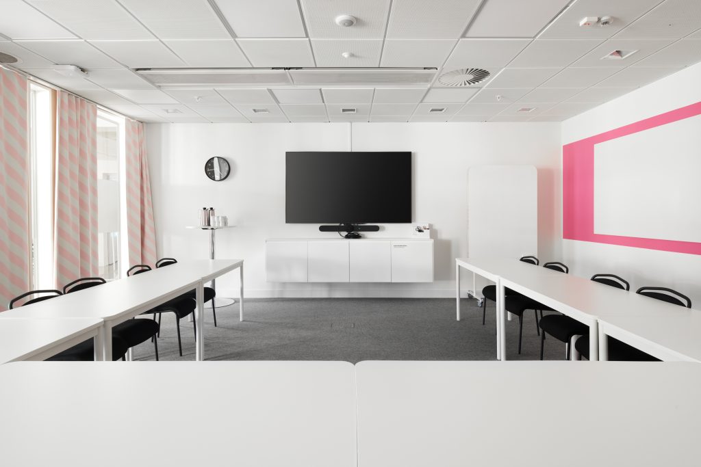 A conference room with pink details and textiles. Chairs and tables lined up in a