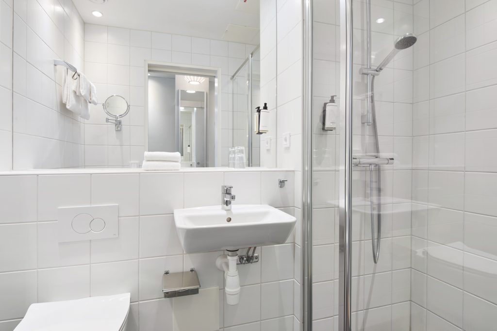 En vy av ett badrum med toalett, tvättställ och dusch med glasväggar.