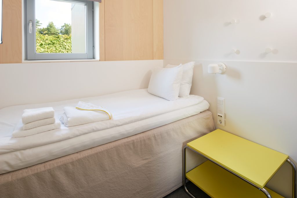 En enkelsäng med ett stort nattduksbord bredvid för förvaring.