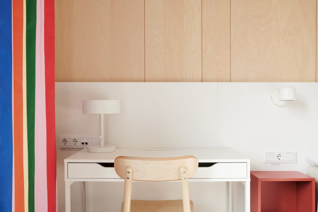 Ett skrivbord med en bordslampa ovanpå och en stol framför.